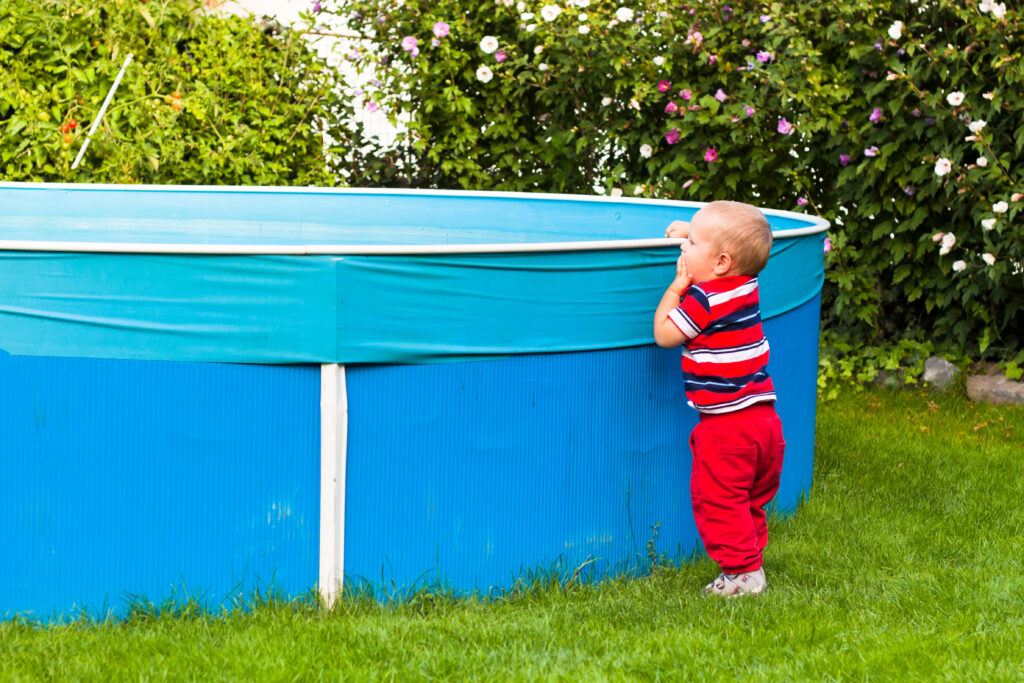Mały chłopiec stoi przy basenie zakrytym pokrywą basenową